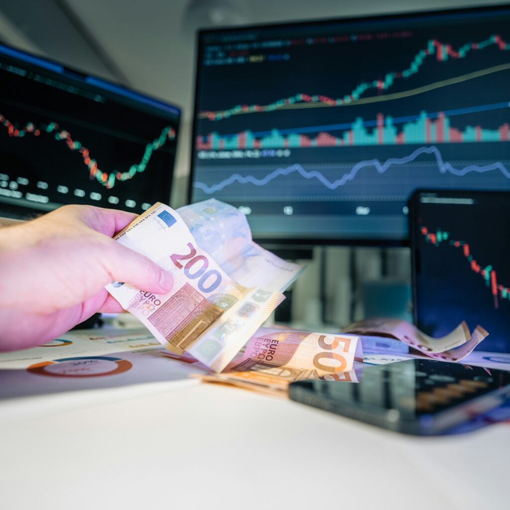 A person with money in his hands as he looks at the stock market